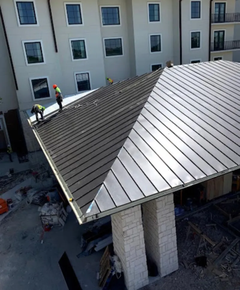 Crew installing standing seam metal roof panels on a commercial project in Le Mars